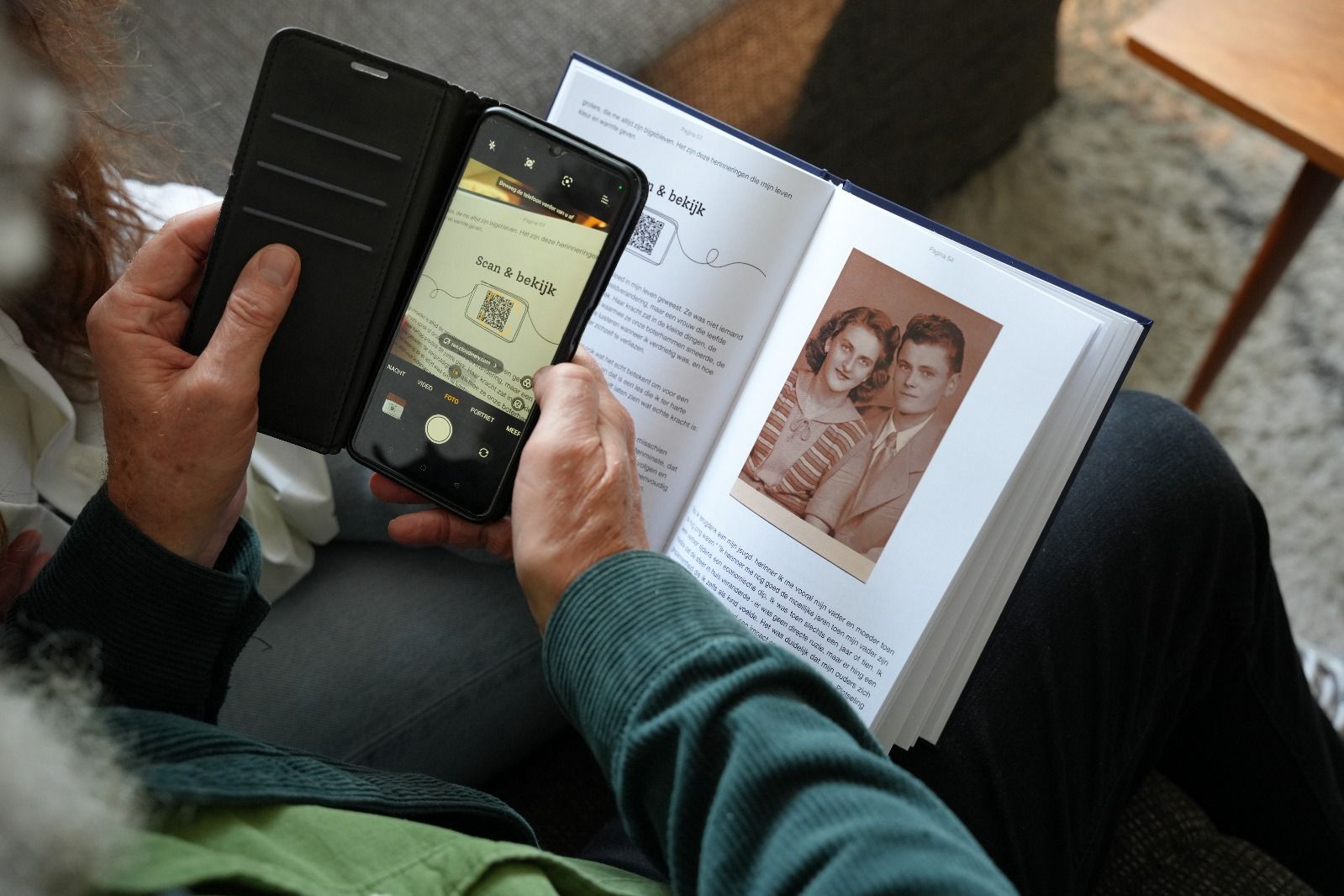 Handen houden het levensboek vast met foto en telefoon die de app toont