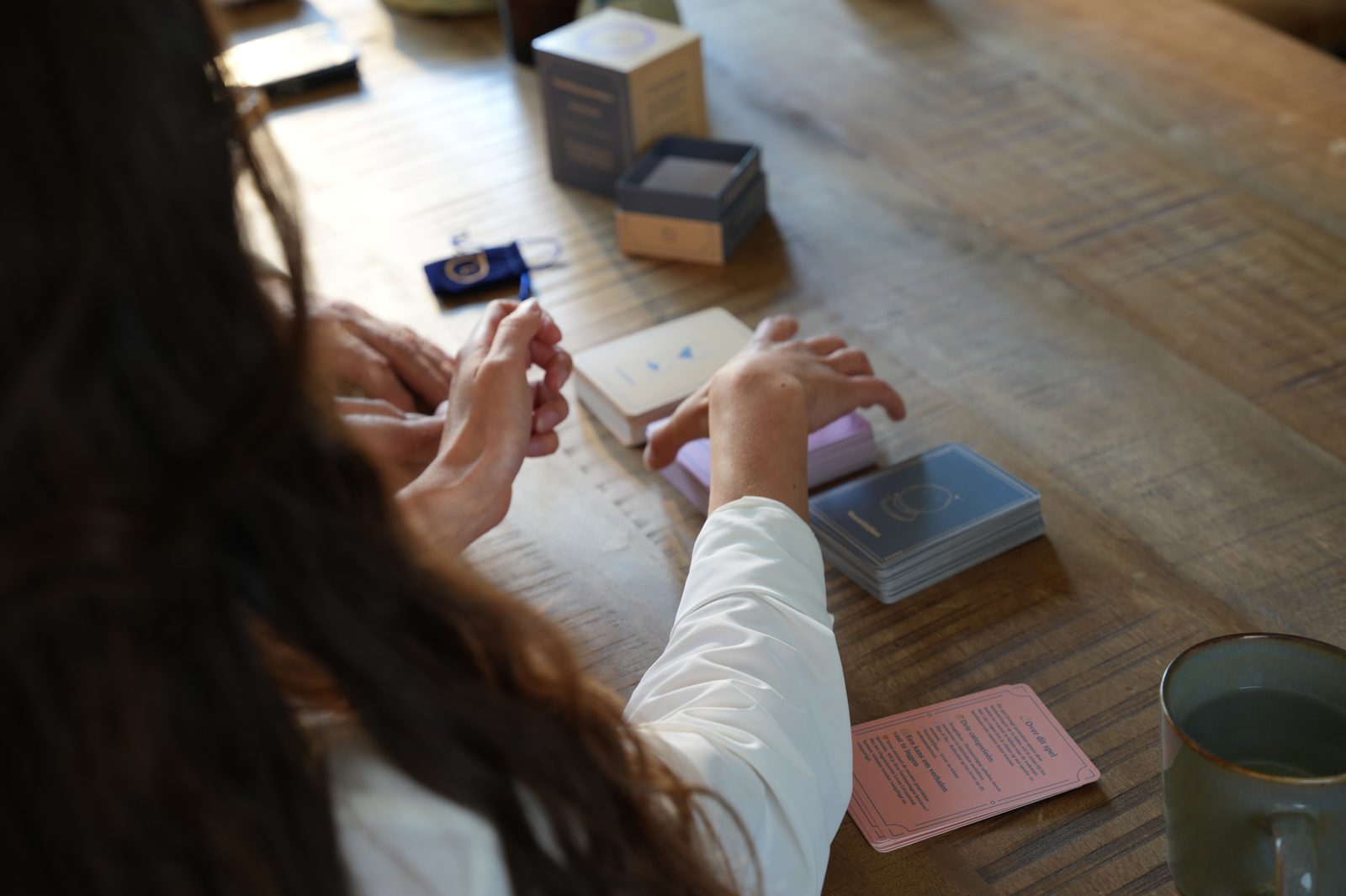 Vrouw pakt een gesprekskaart aan tafel met koffie