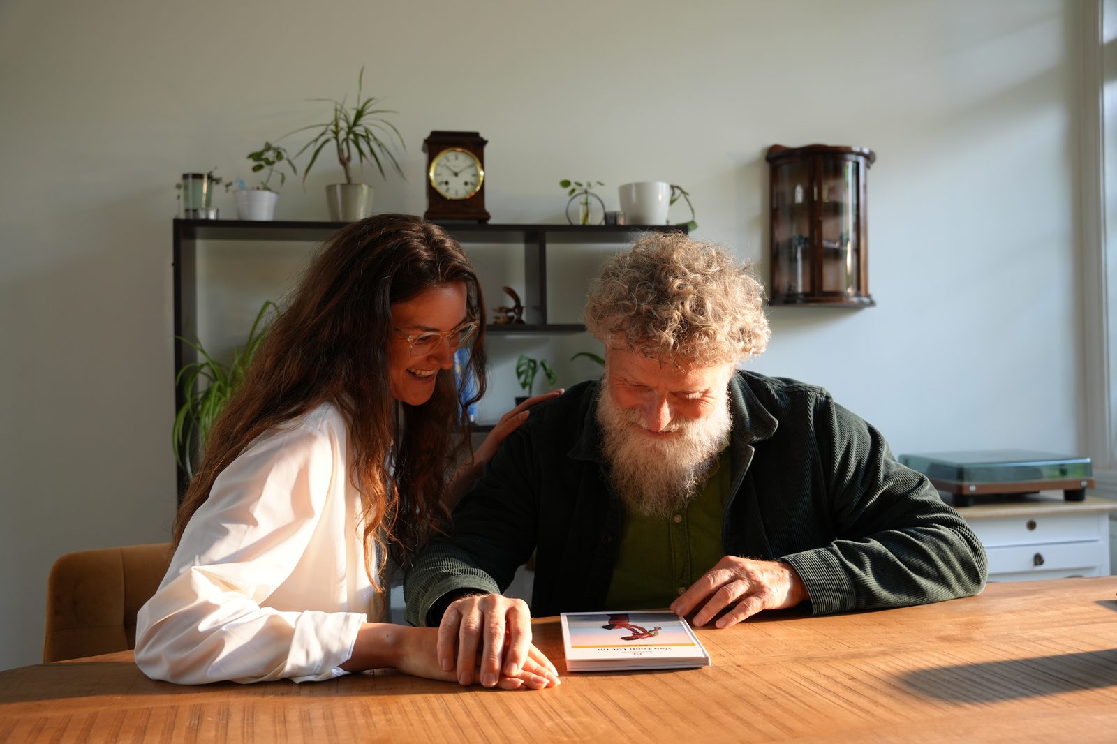 Jongere vrouw en oudere man kijken samen naar het levensboek aan tafel
